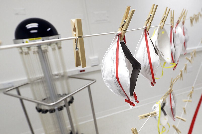 AP file photo by Mark Humphrey / In this April 21, 2020 photo, masks used to protect health care workers during the COVID-19 pandemic hang from a line after being sanitized with ultraviolet light at Vanderbilt University Medical Center in Nashville, Tenn.