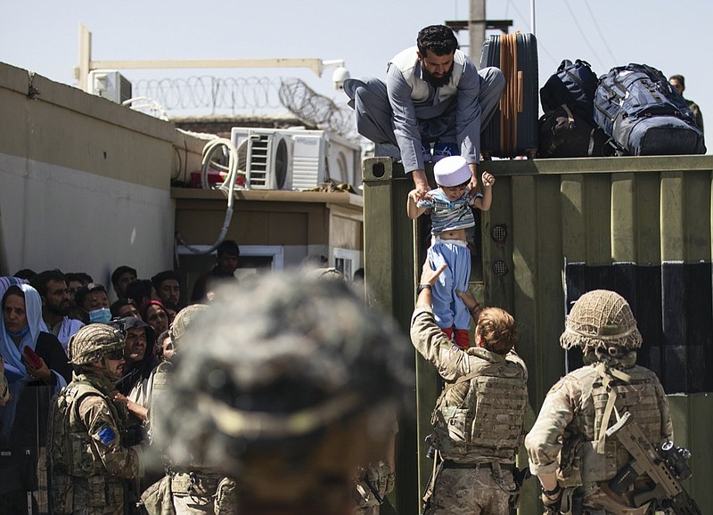 In this image provided by the U.S. Army, an Afghan man hands his child to a British Paratrooper assigned to 2nd Battalion, Parachute Regiment while a member of 1st Brigade Combat Team, 82nd Airborne Division conducts security at Hamid Karzai International Airport in Kabul, Afghanistan, Thursday, Aug 26, 2021. (U.S. Army via AP)


