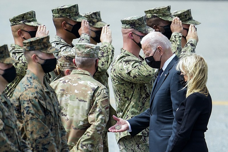 President Joe Biden holds a presidential challenge coin as he speaks with Air Force Mortuary Affairs Operations Air Force Col. Chip Hollinger and others after participating in a casualty return Sunday, Aug. 29, 2021, at Dover Air Force Base. Biden embarked on a solemn journey Sunday to honor and mourn the 13 U.S. troops killed in the suicide attack near the Kabul airport as their remains return to U.S. soil from Afghanistan. First lady Jill Biden is at right. (AP Photo/Manuel Balce Ceneta)