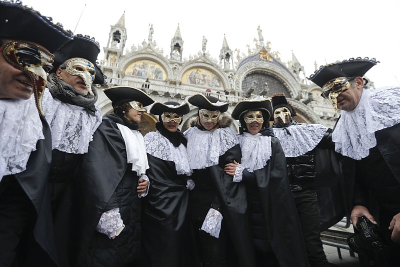 FILE - In this Feb.11, 2017 file photo, men wears masks, some of them pest doctor masks, in St. Mark's Square in Venice, Italy. This carnival mask derives from 16th century doctors wearing beak-nosed masks filled with aromatic herbs to cleanse the air they breathed when treating the sick. Venice's central place in the history of battling pandemics and pestilence will come into focus at this year's Venice Film Festival, which opens Wednesday, Sept. 1, 2021, with the premiere of Pedro Almodovar's in-competition "Madres Paralelas" (Parallel Mothers), which he developed during Spain's 2020 coronavirus lockdown, one of the harshest in the West. (AP Photo/Luca Bruno)