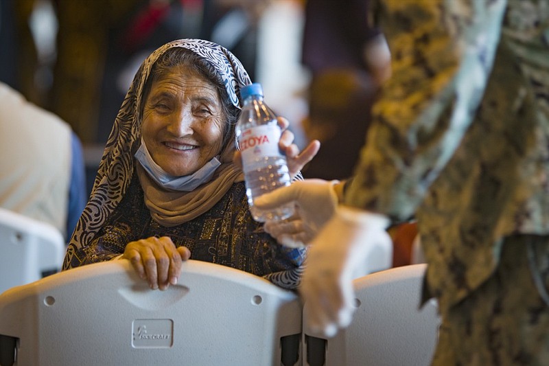 A woman from Afghanistan smiles after being given a bottle of water after disembarking from a U.S. airforce plane at the Naval Station in Rota, southern Spain, Tuesday Aug. 31, 2021. The United States completed its withdrawal from Afghanistan late Monday, ending America's longest war. (AP Photo/ Marcos Moreno)