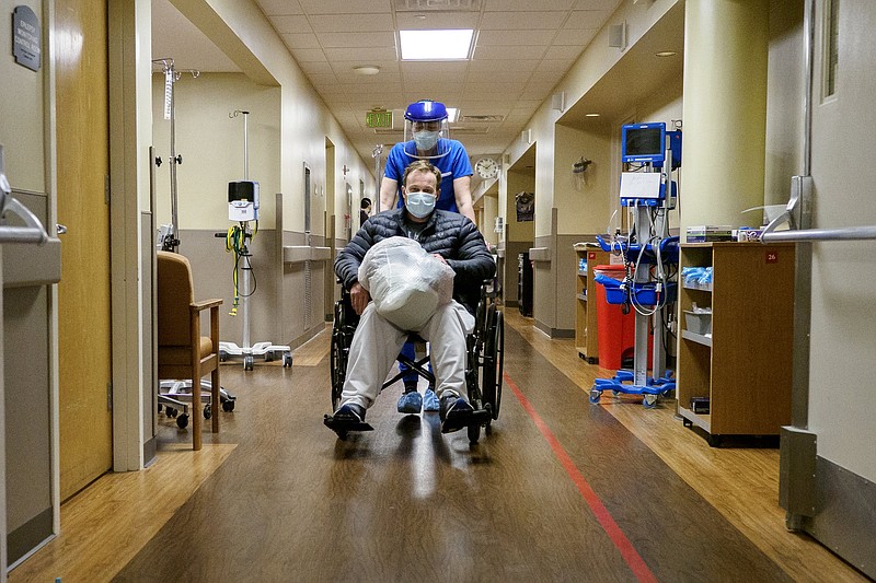 Staff photo by C.B. Schmelter / Clinical Staff Leader Nurse Ashley Engen pushes Taft Butcher in a wheelchair as he is discharged on the COVID floor at Erlanger on Monday, Feb. 22, 2021 in Chattanooga, Tenn.