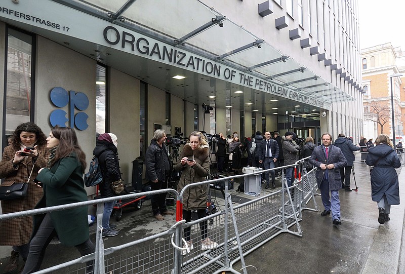 FILE - In this Friday March 6, 2020 file photo, people stand outside the headquarters of the Organization of the Petroleum Exporting Countries, OPEC, in Vienna, Austria. Members of the OPEC oil producing cartel and allied countries led by Russia signed off Wednesday Sept. 1, 2021, on gradually increasing production as the global economy and demand for fuel continue to recover from the worst of the coronavirus pandemic. (AP Photo/Ronald Zak, file)