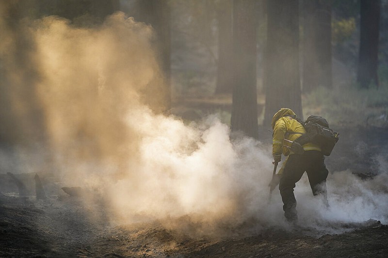 A firefighter mops up hot spots near South Lake Tahoe, Calif., Wednesday, Sept. 1, 2021. Authorities are reporting progress in the battle to save communities on the south end of Lake Tahoe from a huge forest fire. (AP Photo/Jae C. Hong)