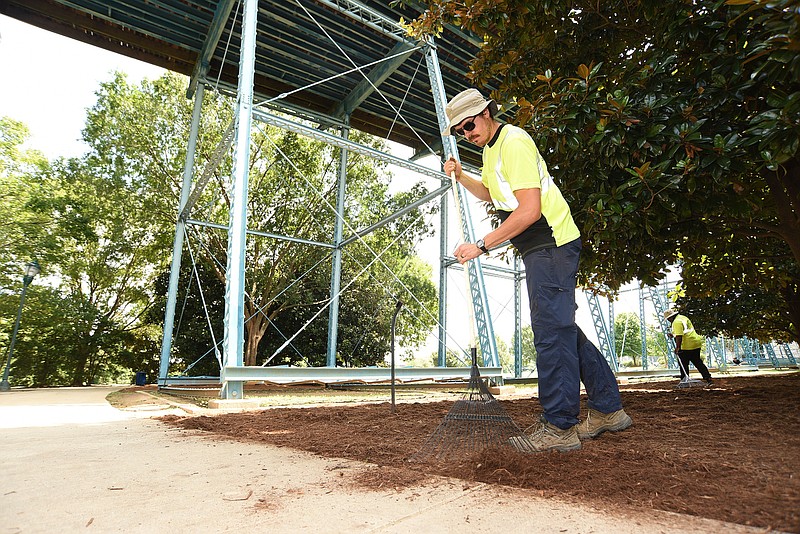 Staff Photo by Matt Hamilton / James Stockdale, front, and Marshawn Sims work to replenish mulch on Friday in Coolidge Park. Workers trimmed trees and bushes as they prepared the park for the upcoming musical festival on Friday, September 3, 2021. 