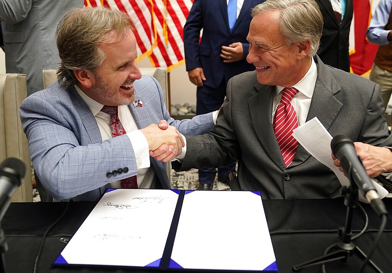 Texas Gov Greg Abbott and State Sen. Bryan Hughes, R-Mineola, shake hands after Abbott signed Senate Bill 1, also known as the election integrity bill, into law in Tyler, Texas, Tuesday, Sept. 7, 2021. The sweeping bill signed Tuesday by the two-term Republican governor further tightens Texas' strict voting laws. (AP Photo/LM Otero)