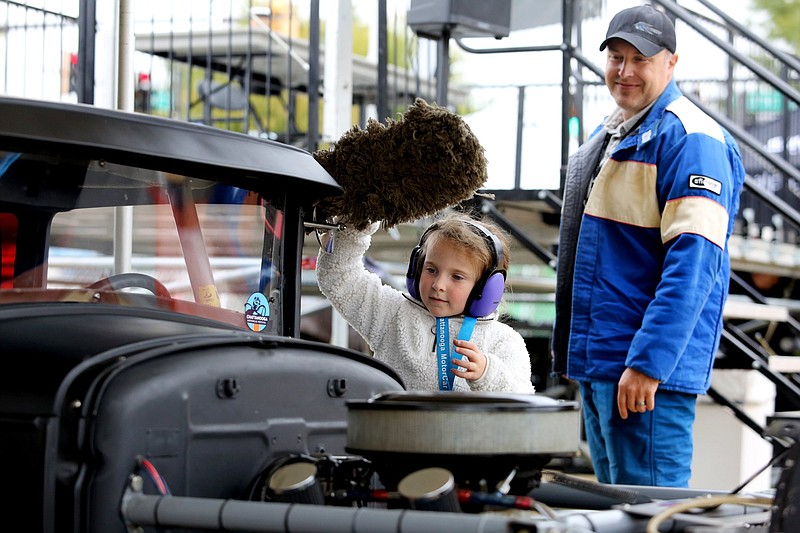 Staff photo by Erin O. Smith / Charlotte Albertson, 6, cleans off her dad's car as he looks on during the Chattanooga MotorCar Festival time trials along Riverfront Parkway in 2019. The event will return to Chattanooga in October.