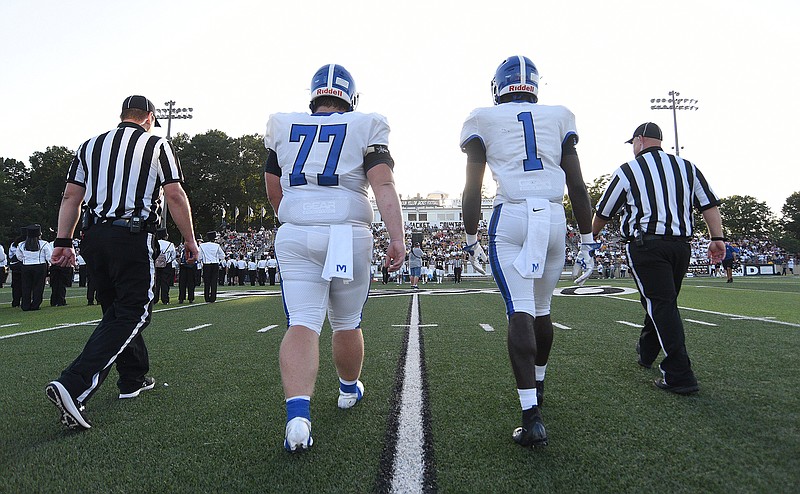 Staff photo by Matt Hamilton / McCallie's Cooper Rumfelt (77) and Kenzy Paul (1) walk alongside officials to midfield for the pregame coin toss on Aug. 27 in Calhoun, Ga. McCallie, the back-to-back reigning TSSAA Division II-AAA state champion, is 3-0 this season, but some Chattanooga-area schools have only played once in the first month due to COVID-19 protocol.