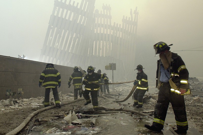 FILE - In this Sept. 11, 2001 file photo, firefighters work beneath the destroyed mullions, the vertical struts which once faced the soaring outer walls of the World Trade Center towers, after a terrorist attack on the twin towers in New York.   Families of the victims of the worst terror attack on the United States in history gathered Wednesday, Sept. 11, 2013,  to mark their 12th anniversary with a moment of silence and the reading of names.  The Sept. 11, 2001 attacks in New York City and Washington killed almost 3,000 people and lead to a war in Afghanistan. (AP Photo/Mark Lennihan)