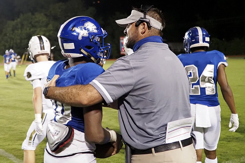 Staff photo / Red Bank football coach Chris Brown helps running back AD Crutcher up after he was tackled during the Lions' home game against Soddy-Daisy in August 2020. The Lions hosted the Trojans again on Friday night.