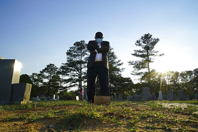 Mortician Shawn Troy stands at the grave of his father, William Penn Troy Sr., at Hillcrest Cemetery outside Mullins, S.C., on Sunday, May 23, 2021. The elder Troy, who developed the cemetery, died of COVID-19 in August 2020, one of many Black funeral directors to succumb during the pandemic. "I don't think I'll ever get over it," he said. "But I'll get through it." (AP Photo/Allen G. Breed)