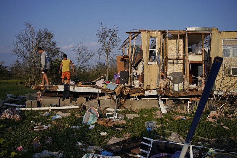 FILE - In this Sept. 4, 2021 file photo, Aiden Locobon, left, and Rogelio Paredes look through the remnants of their family's home destroyed by Hurricane Ida in Dulac, La. Louisiana students, who were back in class after a year and a half of COVID-19 disruptions kept many of them at home, are now missing school again after Hurricane Ida. A quarter-million public school students statewide have no school to report to, though top educators are promising a return is, at most, weeks away, not months. (AP Photo/John Locher, File)