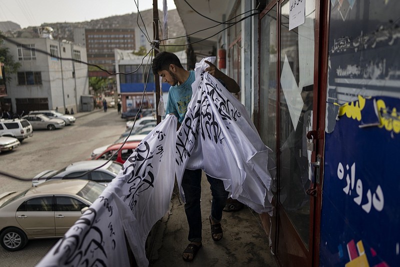 A worker collects newly hand printed Taliban flags in a workshop in Kabul's Jawid market, Afghanistan, Sunday, Sept. 12, 2021. The small flag shop, tucked away in the courtyard of a Kabul market, has documented Afghanistan's turbulent history over the decades with its ever-changing merchandise. Now the shop is filled with white Taliban flags, emblazoned with the Quran's Muslim statement of faith, in black Arabic lettering. (AP Photo/Bernat Armangue)