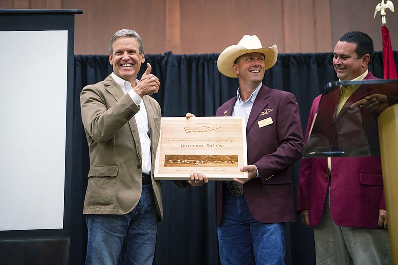 Contributed photo via AP / This photo provided by the State of Tennessee shows Tennessee Gov. Bill Lee receiving an award from the Tennessee Cattlemen's Association in July for having the state press farmers to vaccinate their cattle against disease and reimbursing them, yet when President Joe Biden mandates employers with 100 or more workers to require worker receive free vaccines, Lee calls blasts the plan as a "power grab."