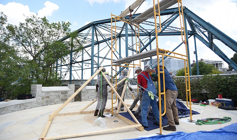 Staff Photo by Matt Hamilton / Workers move the statue of Ed Johnson into place Tuesday. Workers from Pointe General Contractors delivered the bronze statues for the Ed Johnson Memorial which weigh about 350 pounds each on the south end of the Walnut Street Bridge on Tuesday, Sept. 14, 2021.