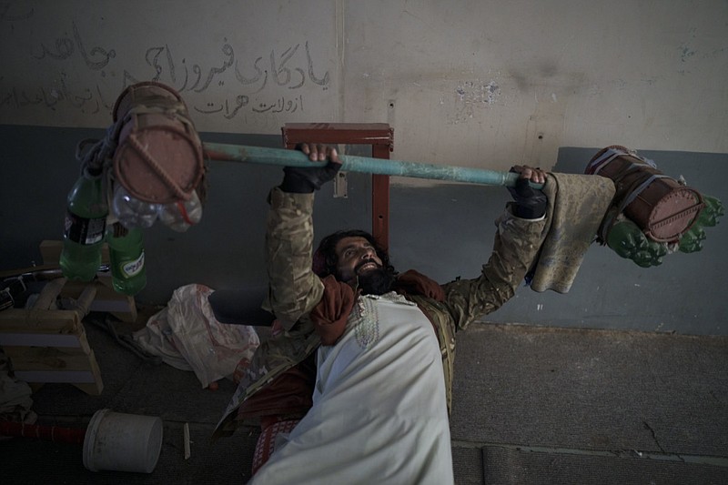 A Taliban fighter lifts a makeshift weight left behind by former prisoners at an empty area of the Pul-e-Charkhi prison in Kabul, Afghanistan, Monday, Sept. 13, 2021. Pul-e-Charkhi was previously the main government prison for holding captured Taliban and was long notorious for abuses, poor conditions and severe overcrowding with thousands of prisoners. Now after their takeover of the country, the Taliban control it and are getting it back up and running, current holding around 60 people, mainly drug addicts and accused criminals. (AP Photo/Felipe Dana)

