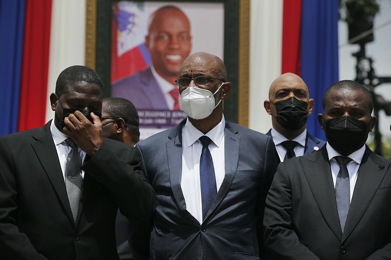 FILE - In this July 20, 2021 file photo, Haiti's designated Prime Minister Ariel Henry, center, and interim Prime Minister Claude Joseph, right, pose for a group photo with other authorities in front of a portrait of slain Haitian President Jovenel Moise at the National Pantheon Museum during a memorial service for Moise in Port-au-Prince, Haiti. Haiti's chief prosecutor has asked a judge to charge Henry in the slaying of his predecessor and barred him from leaving the country. (AP Photo/Joseph Odelyn, File)


