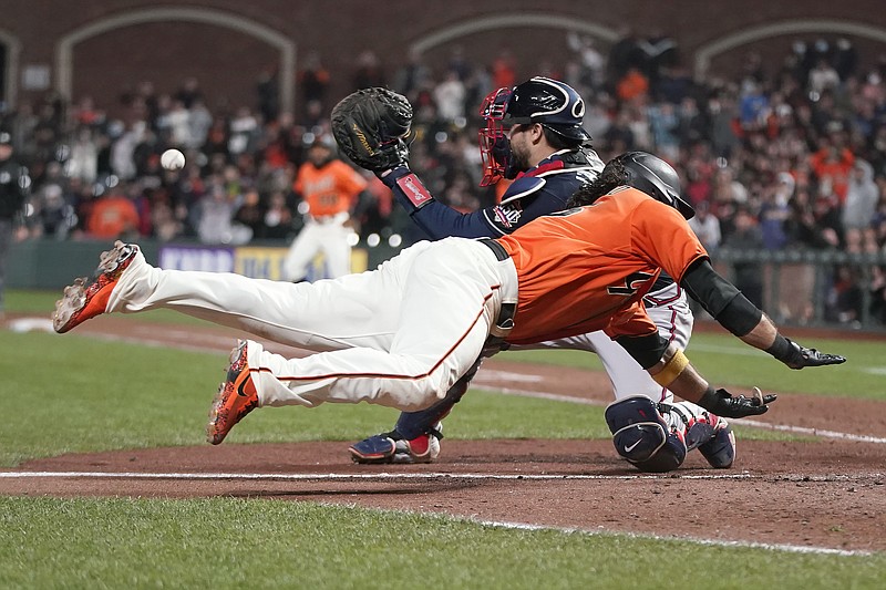 AP photo by Jeff Chiu / The San Francisco Giants' Brandon Crawford slides into home plate to score the winning run past Atlanta Braves catcher Travis d'Arnaud during the 11th inning of Friday night's game in San Francisco.