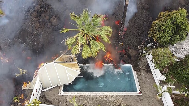 Hot lava reaches a swimming pool after an eruption of a volcano on the island of La Palma in the Canaries, Spain, Monday, Sept. 20, 2021. Giant rivers of lava are tumbling slowly but relentlessly toward the sea after a volcano erupted on a Spanish island off northwest Africa. The lava is destroying everything in its path but prompt evacuations helped avoid casualties after Sunday's eruption. (Europa Press via AP)
