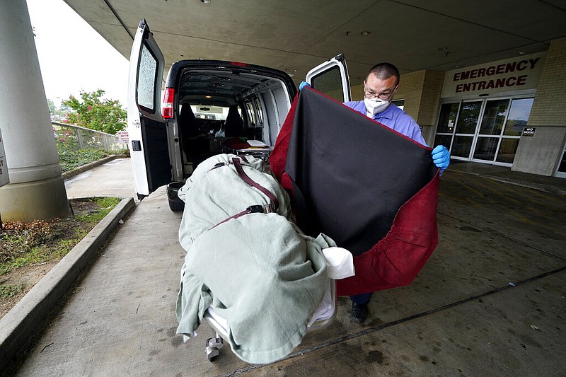 In this Aug. 18, 2021, file photo, an employee of a local funeral home covers the body of a COVID-19 patient patient who died as he prepares to take it away from a loading dock, at the Willis-Knighton Medical Center in Shreveport, La. COVID-19 deaths in the U.S. have climbed to an average of more than 1,900 a day for the first time since early March, with experts saying the virus is preying largely on a select group: 71 million unvaccinated Americans. (AP Photo/Gerald Herbert, File)