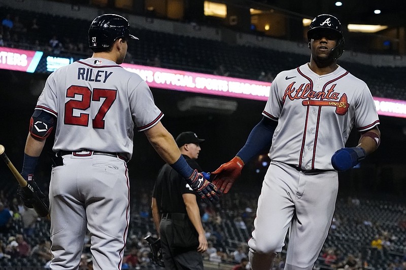 Atlanta Braves' Jorge Soler greets Austin Riley (27) after scoring on a sacrifice fly by Ozzie Albies during the first inning of a baseball game against the Arizona Diamondbacks, Wednesday, Sept. 22, 2021, in Phoenix. (AP Photo/Matt York)