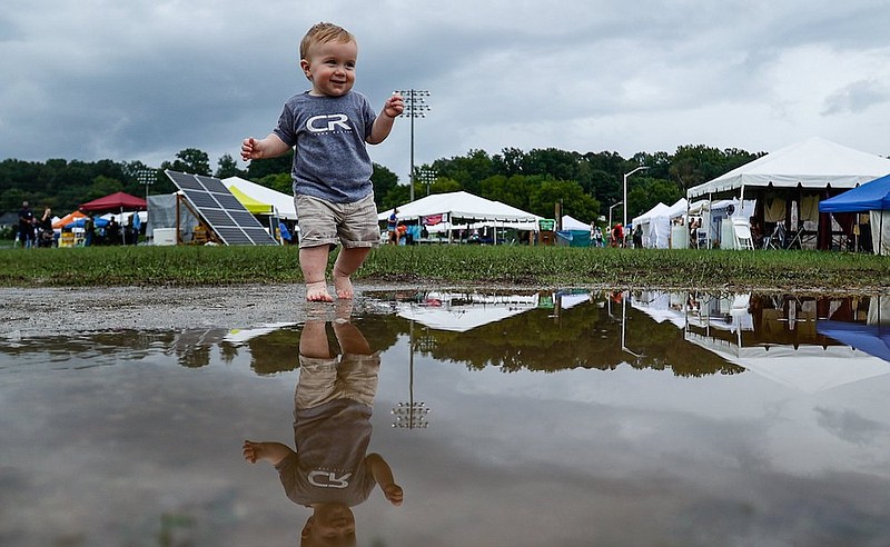 Staff photo by Troy Stolt / 10-month-old Everett Elkins walks into a giant puddle after a heavy rain during day two of Get Off the Grid Fest 2021 at Camp Jordan Park on Saturday, Aug. 21, 2021 in East Ridge, Tenn.