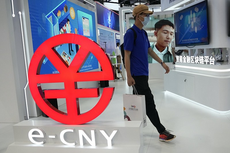 A visitor passes by a logo for the e-CNY, a digital version of the Chinese Yuan, displayed during a trade fair in Beijing, China, Sunday, Sept. 5, 2021. (AP Photo/Ng Han Guan)


