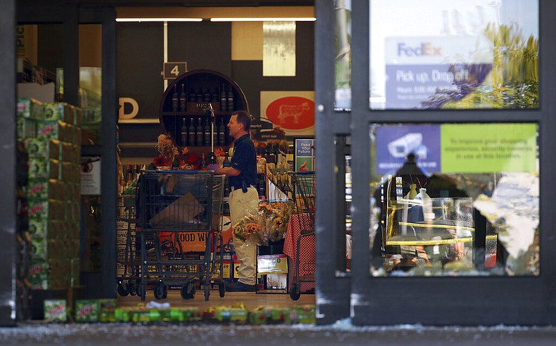 A law enforcement officer takes pictures of the crime scene at a Kroger store in Collierville, Tenn., on Friday, Sept. 24, 2021. Police say a gunman, who has been identified as a third-party vendor to the store, attacked people Thursday and killed at least one person and wounded others before being found dead of an apparent self-inflicted gunshot wound.(Patrick Lantrip/Daily Memphian via AP)