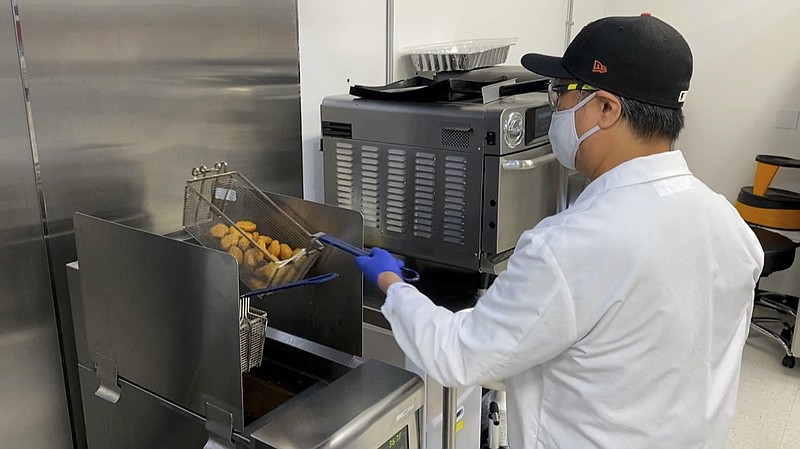 Nathan Foot, R&D chef at Impossible Foods, takes its new meatless nuggets out of a deep fryer in the company's test kitchen on Sept. 21, 2021 in Redwood City, Calif. The plant-based nuggets taste are designed to taste like chicken. (AP Photo/Terry Chea)