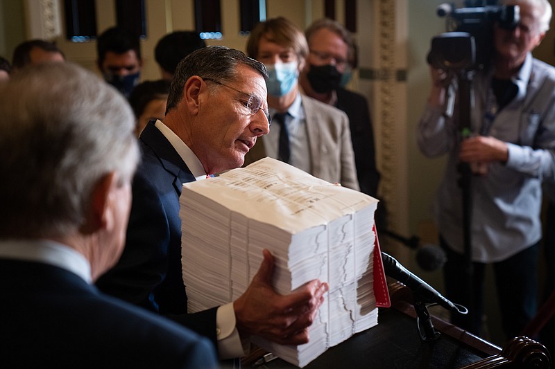 Photo by Sarahbeth Maney of The New York Times / Sen. John Barrasso, R-Wyoming, holds a stack of papers representing the $3.5 trillion spending bill during a weekly news conference at the Capitol in Washington on Tuesday, Sept. 28, 2021.
