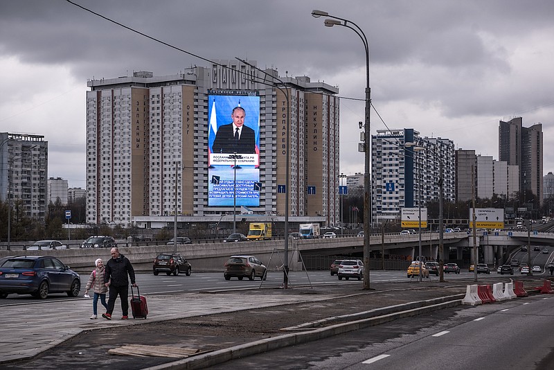 File photo by Sergey Ponomarev of The New York Times) / — A photo of President Vladimir Putin is displayed on a monitor on the side of a hotel on the outskirts of Moscow during his annual address on April 21, 2021. Putin was one of several powerful political figures named in the Pandora Papers report.