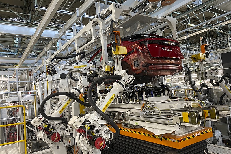 Robotic arms put in the electric vehicle powertrain into the Ariya model in the assembly line at Nissan's Tochigi plant in Kaminokawa town, Tochigi prefecture, Japan, Friday, Oct. 8, 2021. Nissan's "intelligent factory" hardly has any human workers. The robots do the work, including welding and mounting. They do the paint jobs and inspect their own paint jobs. (AP Photo/Yuri Kageyama)