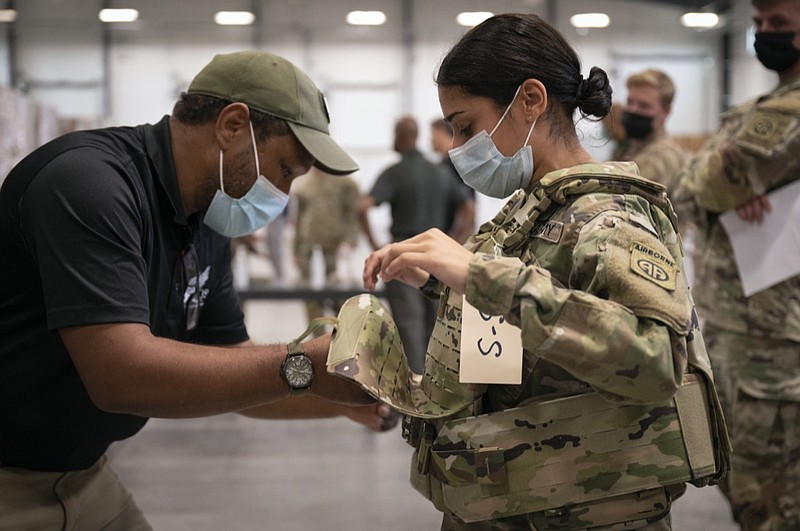 In this image provided by the U.S. Army, Sgt. Katiushka Rivera, a soldier assigned to the 82nd Airborne gets fitted for a modular scalable vest (MSV) during a fielding event in Fort Bragg, N.C., on Sept. 13, 2021. The Army for the first time, began handing out armor that now comes in three additional sizes, and can be adjusted in multiple ways to fit better and allow soldiers to move faster and more freely. The so-called "modular, scalable vest" was is being distributed to soldiers at Fort Bragg, N.C., along with new versions of the combat shirt that are tailored to better fit women, with shorter sleeves and a flare at the bottom where it hits their hips. (Jason Amadi/U.S. Army via AP)