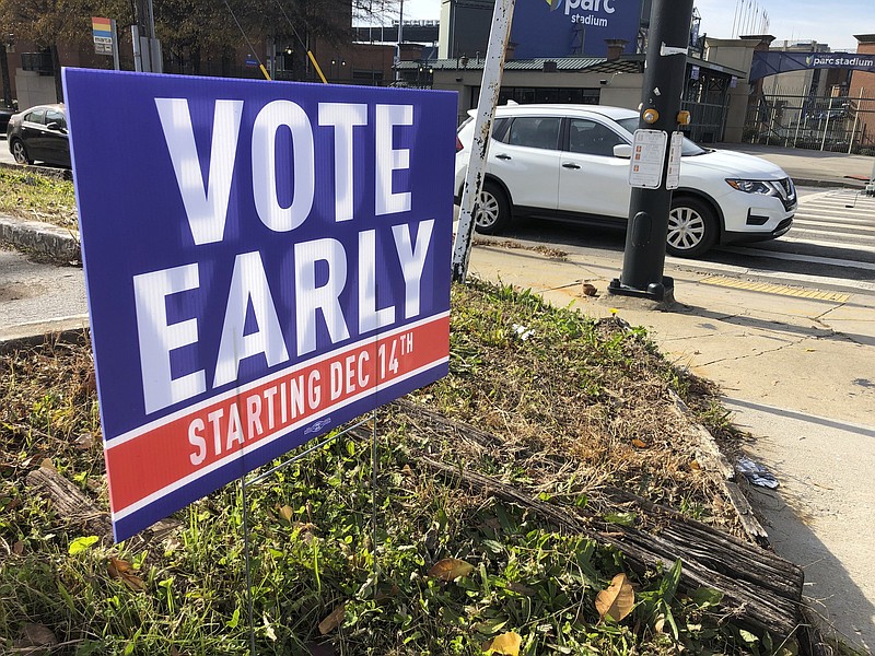 FILE - In this Dec. 11, 2020 file photo, a sign in an Atlanta neighborhood urges people to vote early in Georgia's two U.S. Senate races. The leader of a national conservative group is taking credit for secretly helping to write laws tightening voting rules in several Republican-controlled states and says the group has secretly guided legislation in Arizona, Georgia and Iowa. (AP Photo/Jeff Amy, File)