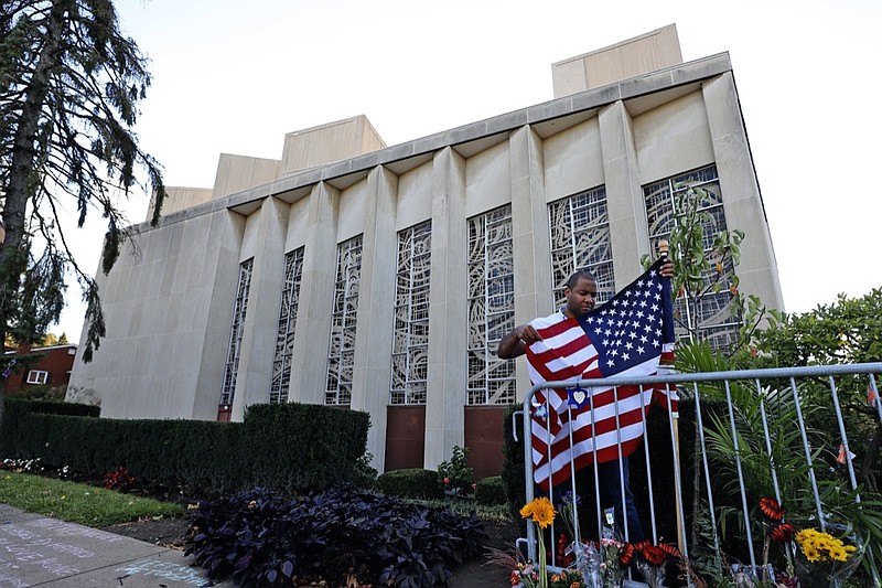 FILE - In this Oct. 27, 2019 file photo a man places an American flag outside the Tree of Life synagogue in Pittsburgh on the first anniversary of the shooting at the synagogue, that killed 11 worshippers. An evidentiary hearing in the case of Robert Bowers a western Pennsylvania truck driver accused of killing 11 people at the Pittsburgh synagogue in 2018, is expected to get underway inside a federal courtroom in Pittsburgh on Tuesday, Oct. 12, 2021. (AP Photo/Gene J. Puskar, File)

