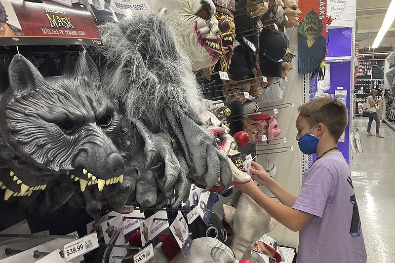 A young customer looks at a Halloween mask at a Party City store, Wednesday, Oct. 6, 2021, in Miami.  Americans continued to spend at a solid clip in September despite rising prices and snarled global supply chains that are limiting the flow of goods. Retail sales rose a seasonally adjusted 0.7%  in September  from the month before, the U.S. Commerce Department said Friday, Oct. 15.  (AP Photo/Marta Lavandier)