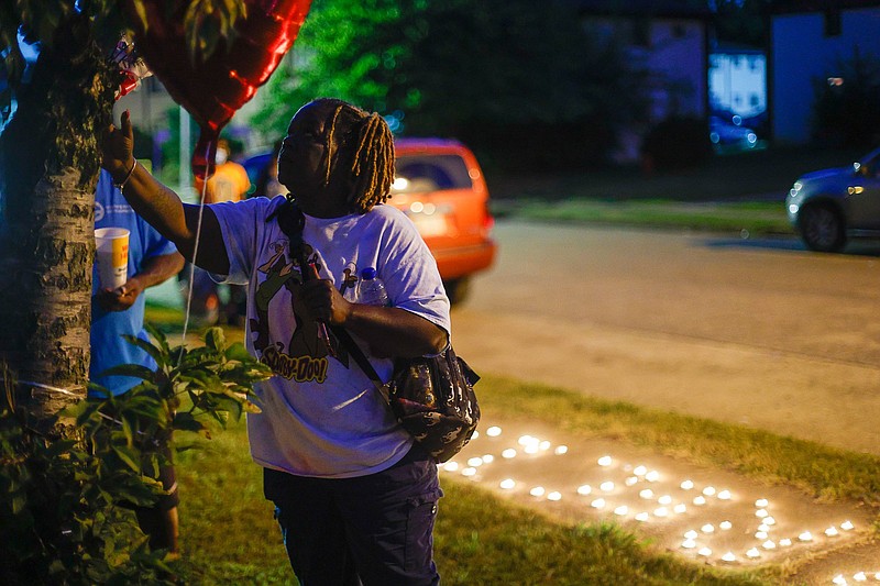 Staff photo by Troy Stolt / Melicha Calhoun adds flowers to a memorial set up in memory of LaBrecia Dews on the 1100 block of Grove Street on Tuesday, Sept. 28, 2021 in Chattanooga, Tenn. Dews was one of two women killed during a shooting at a block party on Grove Street late Saturday.