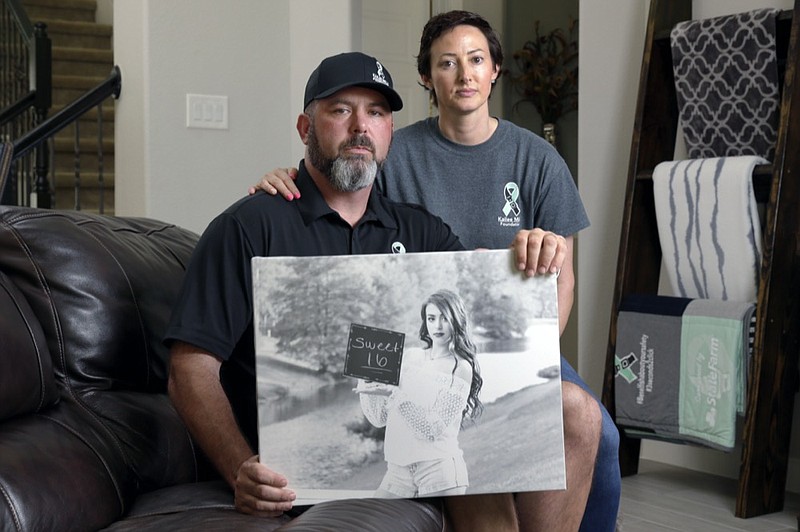 In this Oct. 12, 2021, photo, David and Wendy Mills, parents of Kailee Mills who was killed four years ago in an automobile accident when riding in the back seat without a seat belt, with a photo of their daughter at their home in Spring, Texas. The teenager was riding in the back seat of a car to a Halloween party in 2017 just a mile from her house when she unfastened her seat belt to slide next to her friend and take a selfie. Moments later, the driver veered off the road and the car flipped, ejecting her. (AP Photo/Michael Wyke)


