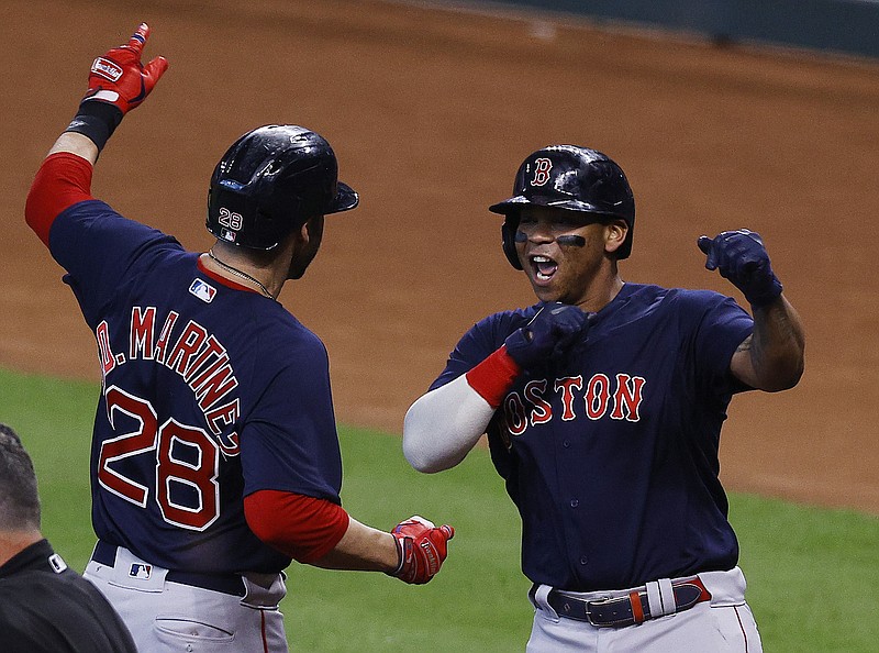 The Galveston County Daily News photo by Kevin M. Cox via AP / Designated hitter J.D. Martinez, left, and third baseman Rafael Devers celebrate after Martinez hit a grand slam for the Boston Red Sox in the first inning of Game 2 of their AL Championship Series against the Houston Astros on Saturday night. Devers hit a grand slam in the second inning, and the Red Sox went on to win 9-5.