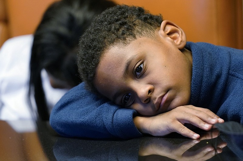 In this Sept. 23, 2021, photo Jhaimarion, 10, reacts as he listens to his mother, Krystal Archie talking with an Associated Press reporter in Chicago. Archie's three children were present when police, on two occasions, just 11 weeks apart, kicked open her front door and tore through their home searching for drug suspects. She'd never heard of the people they were hunting. Her oldest child, Savannah was 14 at the time; her youngest, Jhaimarion, was seven. They were ordered to get down on the floor. (AP Photo/Nam Y. Huh)