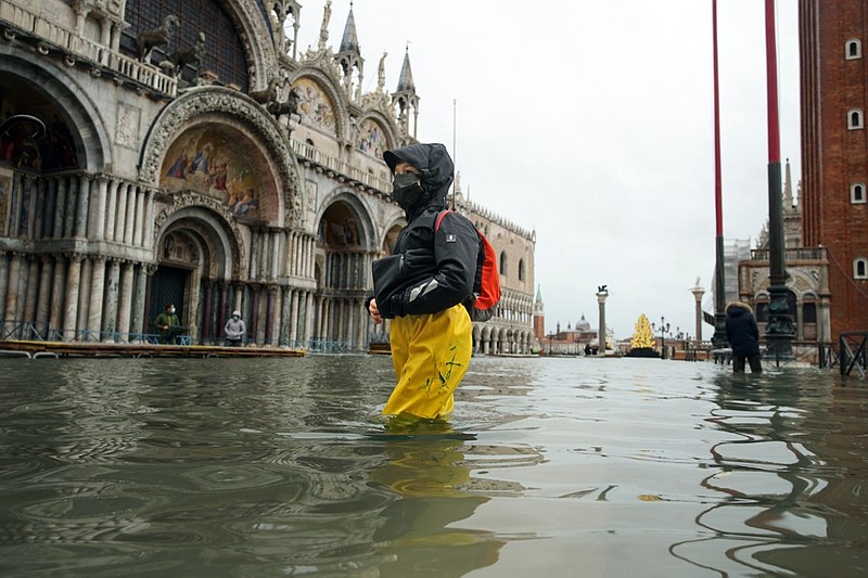 FILE - In this Tuesday, Dec. 8, 2020 file photo, people wade their way through water in flooded St. Mark's Square following a high tide, in Venice, Italy. Lashing winds that pushed 1.87 meters (nearly 6 feet 2 inches) of water into Venice in November 2019 and ripped the lead tiles off St. Mark's Basilica for the first time ever shocked Venetians with the city's second-worst flood in history, but it was the additional four exceptional floods over the next six weeks that triggered fears about the impact of worsening climate change. (Anteo Marinoni/LaPresse via AP, file)
