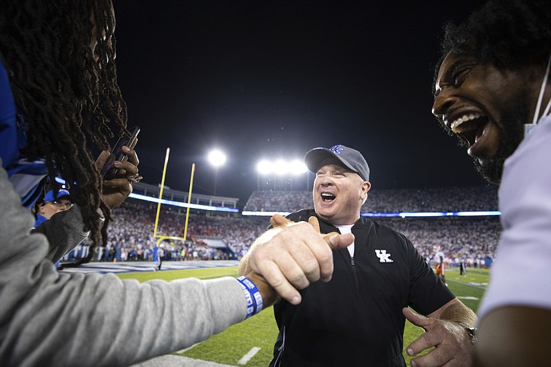 AP photo by Michael Chubb / Kentucky football coach Mark Stoops, center, slaps hands with rapper Waka Flocka Flame, left, after the Wildcats beat Florida on Oct. 2 in Lexington, Ky.