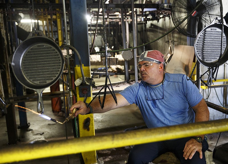 Staff photo by Doug Strickland / A worker blows away bubbles during the cast iron seasoning process at Lodge Manufacturing on Wednesday, June 29, 2016, in South Pittsburg, Tenn.