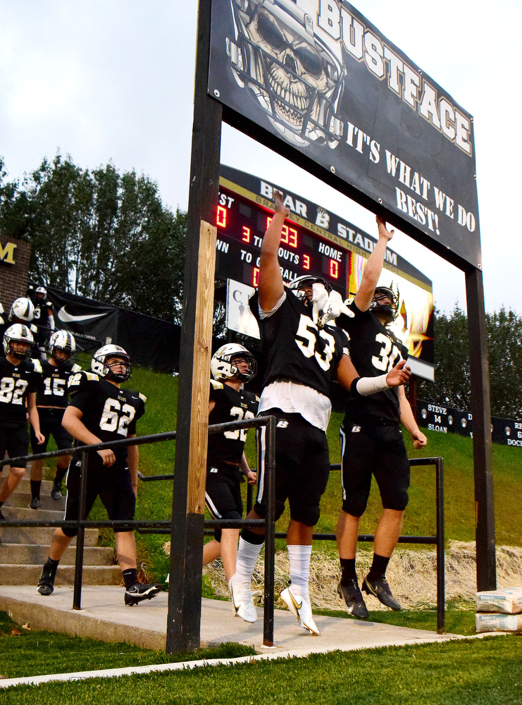 Staff Photo by Robin Rudd / Bubba Whitener (53) and JD Kirkpatrick (30) jump to touch the "Bust Face" sign as the Bears take the field. The Bradley Central Bears hosted the Rhea County Golden Eagles in a TSSAA football game on October 22, 2021.