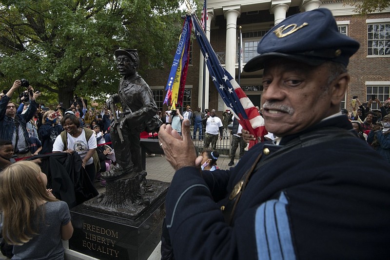 U.S. Colored Troops reenactor Norman Hill applauds at the statue honoring Black enslaved men who enlisted and served in the Civil War after it was unveiled Saturday, Oct. 23, 2021, in Franklin, Tenn. Artist Joe Howard was commissioned by The Fuller Story Project in Franklin to create a bronze monument memorializing Black Civil War Union Army soldiers. (George Walker IV /The Tennessean via AP)