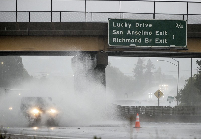 A car drives on Highway 101, which is partially flooded in Corte Madera, Calif., Sunday, Oct. 24, 2021. (AP Photo/Ethan Swope)
