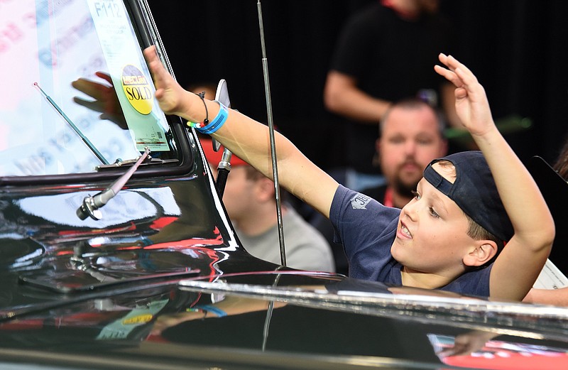 Staff Photo by Matt Hamilton / Hixson resident Luca Henderson, 7, places a "SOLD" sticker on a 1946 Willys Overland Jeep at the Chattanooga Convention Center in downtown Chattanooga on Friday, October 15, 2021. The Chattanooga Motorcar Festival continues Saturday and Sunday. 