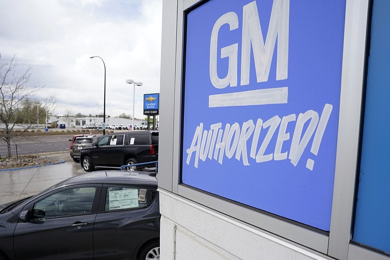 FILE- In this May 2, 2021, file photo, a General Motors sign hangs on the side of a Chevrolet showroom in Englewood, Colo. General Motors announced Tuesday, Oct. 26 2021, that it is planning to install up to 40,000 electric vehicle chargers, starting next year, across the U.S. and Canada as part of a new community charging program. (AP Photo/David Zalubowski, File)