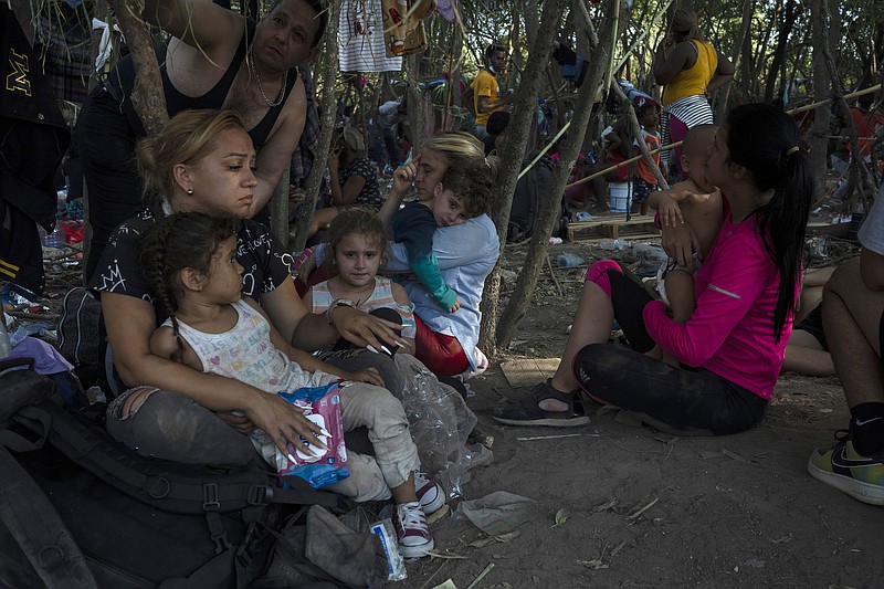 Photo by Verónica G. Cárdenas of The New York Times / A group of migrants from Venezuela seeking asylum rest in the shade near the Del Rio International Bridge before turning themselves in to Border Patrol agents in Del Rio, Texas on Sept. 17, 2021.