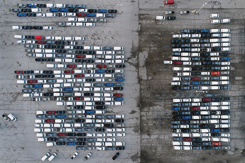Photo by Jeff Roberson of The Associated Press / In this March 24, 2021, file photo, mid-sized pickup trucks and full-size vans are seen in a parking lot outside a General Motors assembly plant where they are produced in Wentzville, Mo. The global shortage of computer chips forced automakers to temporarily close factories including those that build popular pickup trucks.